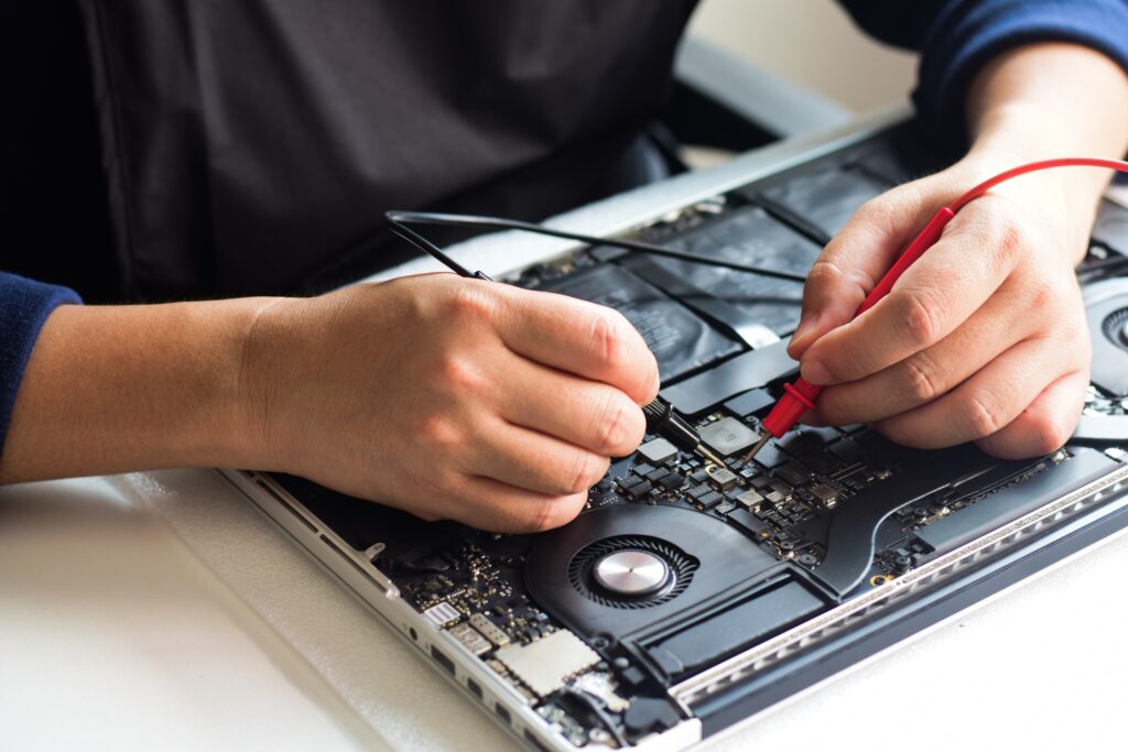 Technician diagnosing a MacBook Pro with a meter for no power issues